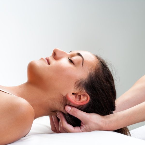 Close up of  chiropractor pressing back of womans head. Therapist doing healing massage with fingers at back of neck.
